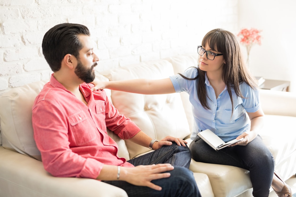Concerned psychotherapist comforting patient